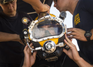 Professioneel duiken volgens inspectie vaak onveilig Marineduiker krijgt hulp bij het opzetten van zijn helm
